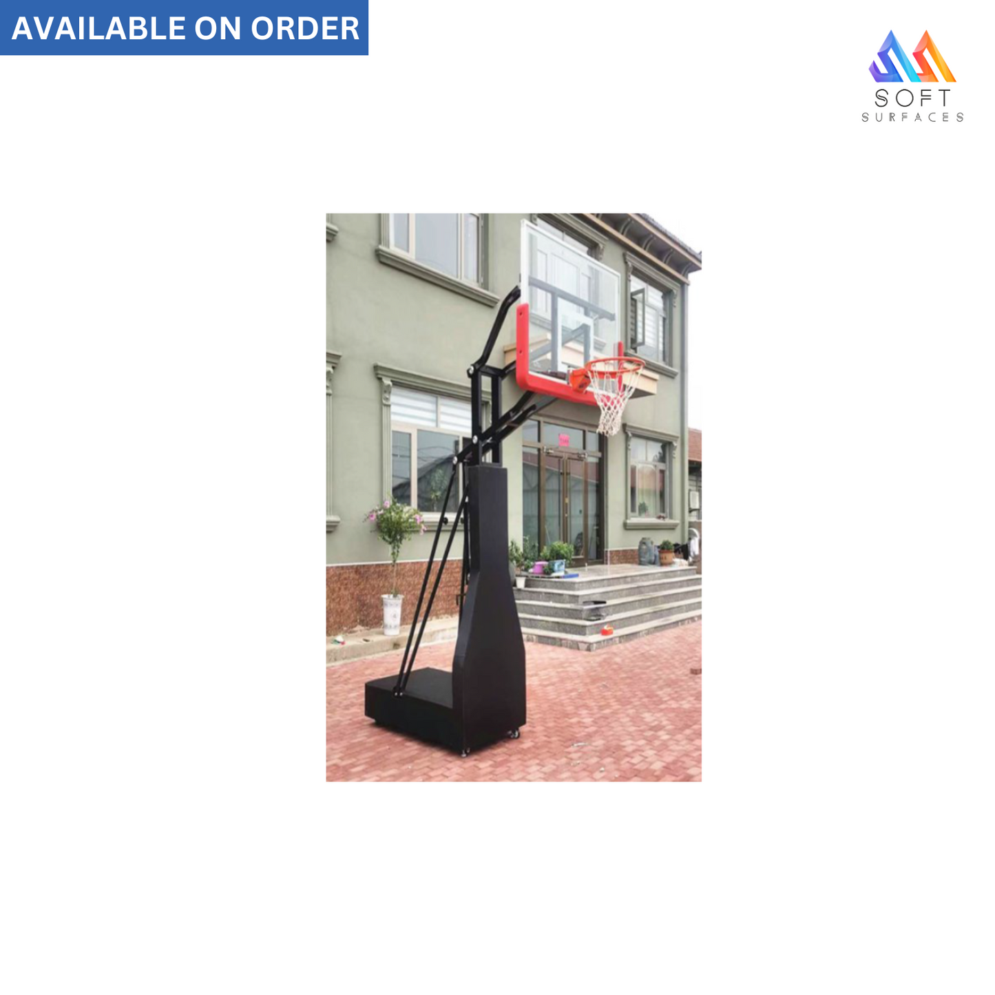 A black height adjustable basketball stand with a backboard, hoop, and net, placed on a driveway in front of a house.
