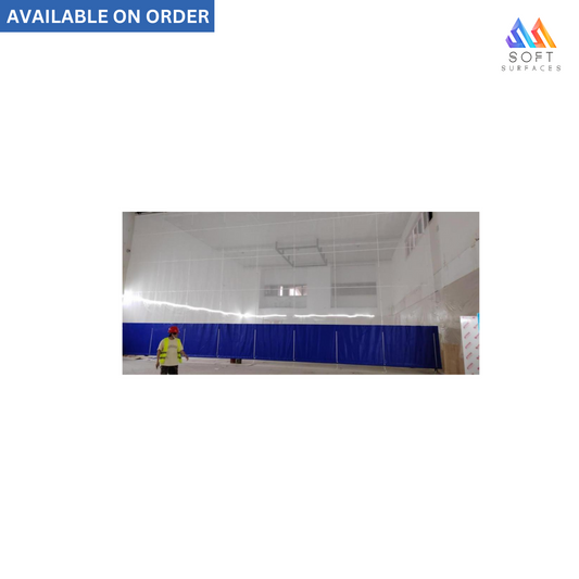 A blue rollup electric divider curtain in a sports gym setting with a person in a reflective vest standing in the foreground.